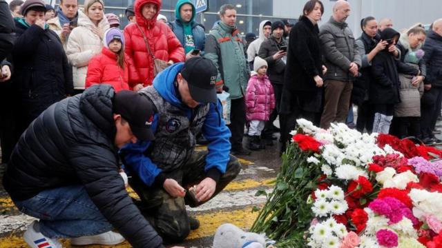 Men light candles at a makeshift memorial at the Crocus City Hall